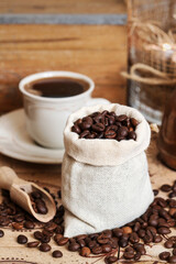 Sticker - Cup of coffee and jute sack with raw grains on the table.