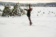 © Ridvan - happy young man jumping over snow in the forest in wintertime and have fun with beautiful mountain background.