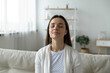 © fizkes - Close up calm young woman relaxing with closed eyes on cozy couch at home, peaceful satisfied beautiful girl sitting on sofa in living room, enjoying lazy weekend, meditating, breathing deep