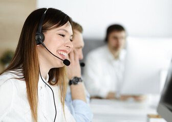 Group of diverse operators at work in call center. Beautiful asian woman sitting in headset at customer service office. Business concept