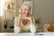 © Anatoliy Karlyuk - Attractive confident mature female entrepreneur working from home, sitting at her workplace, managing papers, looking at camera with broad cheerful smile. Success, confident, job and occupation