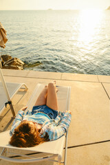 Wall Mural - young woman resting at sun lounger at sunset