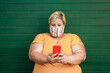 © DisobeyArt - Plus size happy woman using smartphone while wearing protective mask - Curvy people during coronavirus outbreak - Focus on face