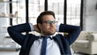 © fizkes - Close up dreamy businessman wearing suit and glasses leaning back in comfortable office chair, dreaming, successful entrepreneur stretching hands, enjoying break, visualizing future, stress relief