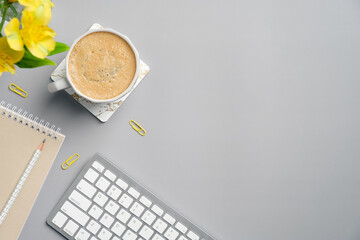 Poster - Flat lay top view keyboard, cup of coffee, paper notebook, yellow stationery and flower on grey office desk table. Minimal style freelancer workspace.