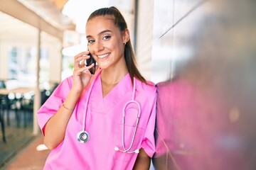 Wall Mural - Young hispanic doctor woman speaking on the smartphone at street of city.