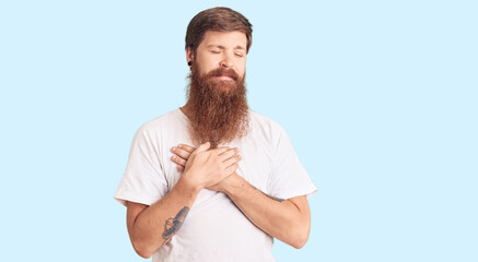 Poster - Handsome young red head man with long beard wearing casual white tshirt smiling with hands on chest with closed eyes and grateful gesture on face. health concept.