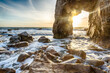 Spectaculaire arche rocheuse naturelle côtière creusée par l'érosion marine, avec rayons du soleil couchant qui traversent l'arche. Quiberon, Bretagne