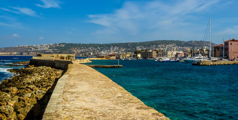 Wall Mural - A view across the harbour wall in Chania harbour, Crete on a bright sunny day