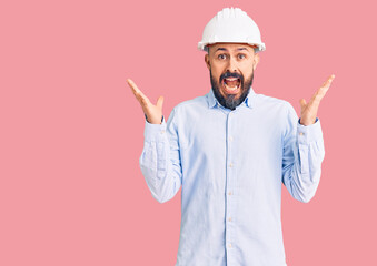 Sticker - Young handsome man wearing architect hardhat celebrating crazy and amazed for success with arms raised and open eyes screaming excited. winner concept