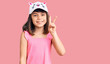 Young little girl with bang wearing funny kitty cap smiling with happy face winking at the camera doing victory sign. number two.