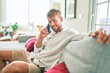 © Krakenimages.com - Handsome caucasian man smiling happy sitting on the sofa at home speaking on the phone