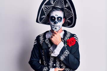 Canvas Print - Young man wearing mexican day of the dead costume over white with hand on chin thinking about question, pensive expression. smiling with thoughtful face. doubt concept.