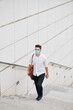 © DragonImages - Handsome young man in medical mask walking up the stairs