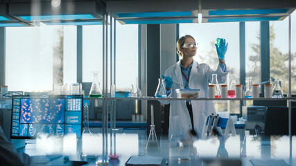 Wall Mural - beautiful female medical scientist wearing white coat and safety glasses uses micropipette while exa