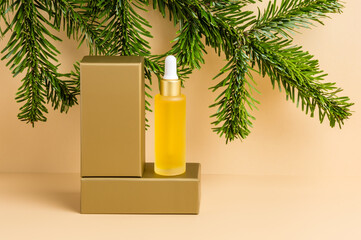 Yellow dropper bottle of serum or oil on golden podium with fir tree on neutral beige background. Organic skin care cosmetics with vitamin C, wellness, spa and beauty treatment concept, product mockup