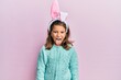 Little beautiful girl wearing cute easter bunny ears sticking tongue out happy with funny expression. emotion concept.