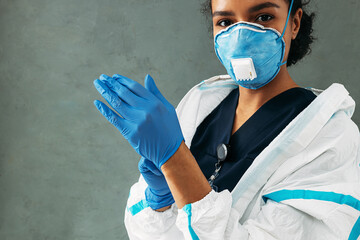 Wall Mural - Young medical worker puts on surgical gloves looking at camera