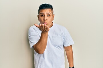 Canvas Print - Young latin man wearing casual white t shirt looking at the camera blowing a kiss with hand on air being lovely and sexy. love expression.