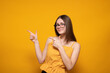 Close up profile of the side portrait of her she is cute cute attractive cheerful amazed joyful straight  pointing with two fingers looks to the side copy of the space isolated on a yellow background
