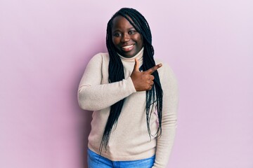 Sticker - Young black woman with braids wearing casual winter sweater cheerful with a smile of face pointing with hand and finger up to the side with happy and natural expression on face