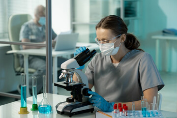 Poster - Young contemporary female scientist studying chemical samples in microscope