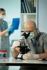 Poster - Mature bald scientist in protective mask and gloves studying chemical samples