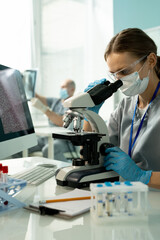 Poster - Clinician in uniform, protective mask, gloves and eyewear using microscope