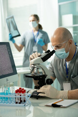 Poster - Mature bald male in protective eyewear, mask and gloves working with microscope