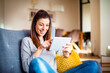 © gzorgz - Happy woman using digital tablet while sitting in the armchair at home