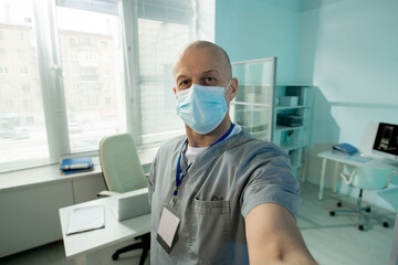 Aufkleber - Bald mature male clinician in protective mask looking at you while making selfie