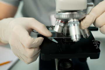 Poster - Gloved hand of scientist or clinician putting glass with chemical sample by lens