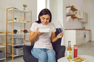 Happy young woman opening container with fresh takeaway lunch and smelling the food