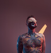 © Fxquadro - Dark and atmospheric room with colourful walls and spotlights and cheerful tattooed guy with naked torso and modern hairstyle weared with mask and sunglasses.