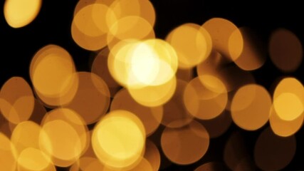Warm orange bokeh lights moving on a black background, abstract lights pattern