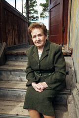 Wall Mural - An old woman ninety years old, sitting on the porch of a village house.