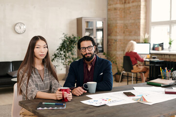 Canvas Print - Young Asian female office worker and her male colleague having coffee at break