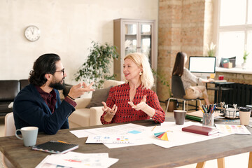 Poster - Young bearded designer and his happy mature female colleague brainstorming