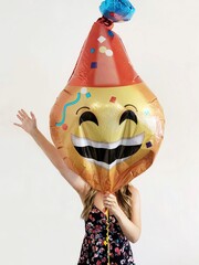 Woman holding a celebration emoji balloon in front of her face