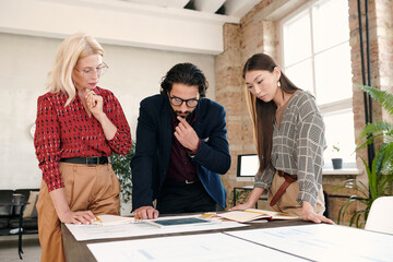 Poster - Pensive intercultural mobile application developers looking at tablet display