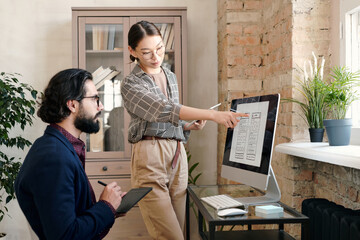 Poster - Young female mobile application developer with tablet pointing at sketch