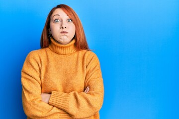 Canvas Print - Beautiful redhead woman with arms crossed gesture puffing cheeks with funny face. mouth inflated with air, catching air.