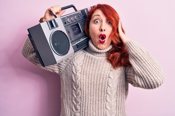 Sticker - Beautiful redhead woman listening to music holding vintage boombox over pink background scared and amazed with open mouth for surprise, disbelief face