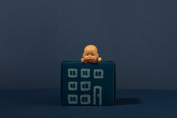 Wall Mural - Baby doll in the paper house on blue background. Blue monday. Isolation. Abandoned child.