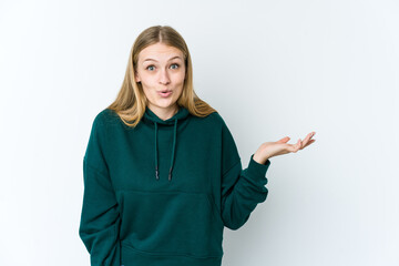 Wall Mural - Young blonde woman isolated on white background impressed holding copy space on palm.