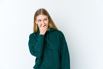 Wall Mural - Young blonde woman isolated on white background thoughtful looking to a copy space covering mouth with hand.