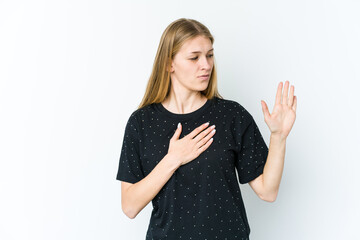 Wall Mural - Young blonde woman isolated on white background taking an oath, putting hand on chest.