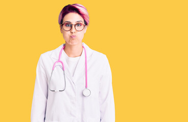 Sticker - Young beautiful woman with pink hair wearing doctor uniform puffing cheeks with funny face. mouth inflated with air, crazy expression.