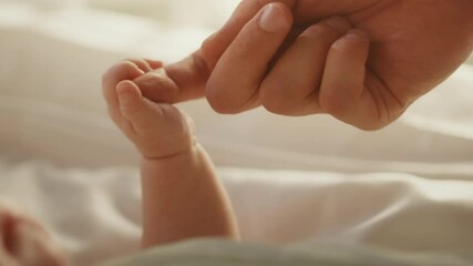close up footage of newborn baby playing with mother's hand and finger while lying on the back in ch