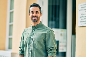 Young hispanic man smiling happy standing at the city.